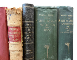A close up of the spine of older books in red, brown, black and other colors. Some of the books date to the 1900s.
