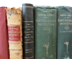 A close up of the spine of older books in red, brown, black and other colors. Some of the books date to the 1900s.