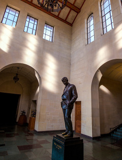 The memorial statue located in Will Rogers Memorial Museum vestibule. The photograph depicts the statue and windows of the structure above.