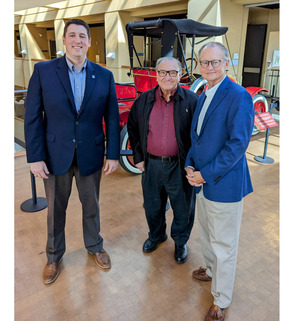 From left to right, Trait Thompson, Bob Burke, and Dr. Bob Blackburn stand near a red antique car at the Oklahoma History Center