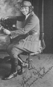 Bessie Coleman in her flying uniform sits at a desk wearing earphones tuned into a radio. Taken in Chicago.