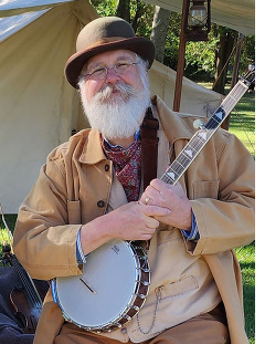 The musical group Zoetrop with Wayne Cantwell holding a banjo and his partner posing at an encampment