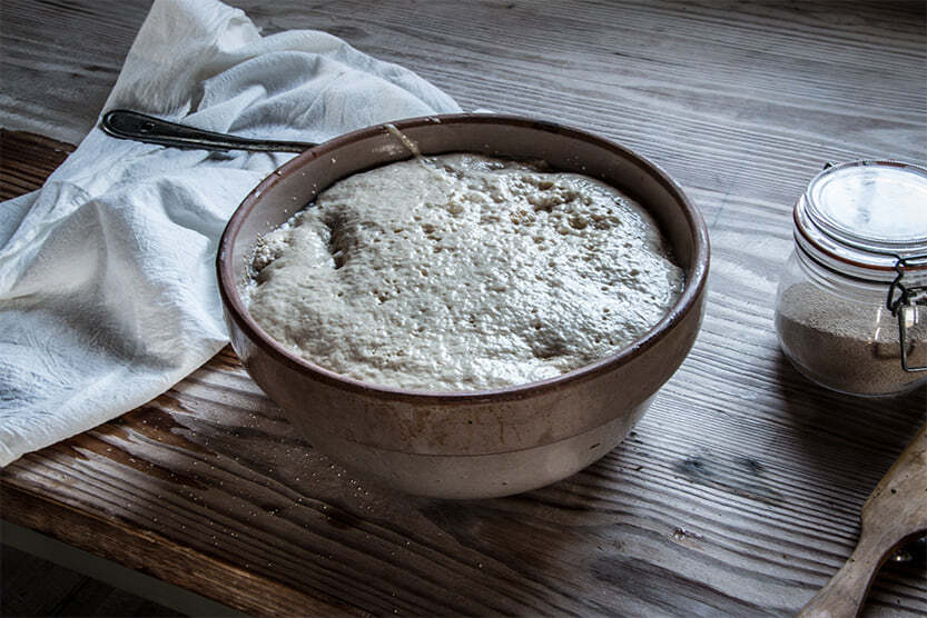 A ceramic bowl with bread dough rising, sitting on a wooden table at Fort Gibson.