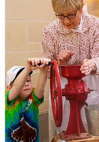 A series of 4 pictures depicting docents leading children through activities and the Will Rogers Museum. Roping, grinding corn