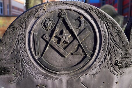 A slate gravestone with an engraving of Mason's symbols intertwined on the head piece