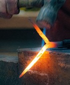 Blacksmith Tom Nelson hammers a hot piece of iron on the anvil in the Blacksmith shop at Cherokee Strip Museum