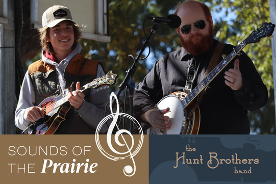 A photo of 2 members of the Hunt Brothers band playing mandolin and banjo at an outdoor venue. The words "Sounds of the Prairie"