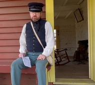 Historian David Reed seated on the bench outside the Sutlers Store in Fort Towson reading a letter