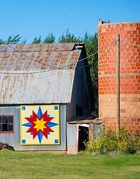 A Barn with a barn quilt displayed near a retired silo.