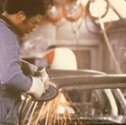 A GM worker grinds a car body with sparks flying around him