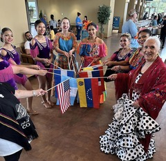 A group gathered at the Oklahoma History Center for the Folklife Festival gather in a circle, joining flags of their respective countries