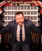 Musician Brett Valiant looks up with the massive keyboard of a theatre organ behind him