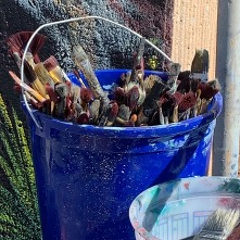 A bucket of paint brushes sit outside the mural painted at the OTM by Bob Palmer