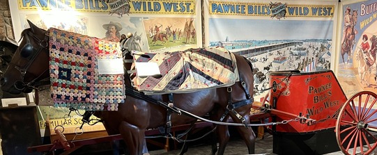 Quilts on display at the Pawnee Bill Ranch and Museum. Quilts are laid over the figure of a horse and chariot from the Wild West Show