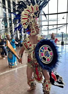 Dancing groups swirling skirts depicted at the Folklife Festival with full costumes. A goup of children listening to a storytelling, and a cowboy cook