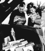 Two women placing books into the back of a car