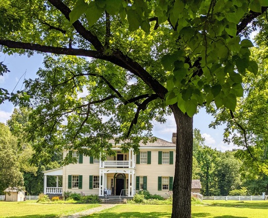 Hunter's Home at the gate of the front of the property. Large shade trees can be viewed in the foreground