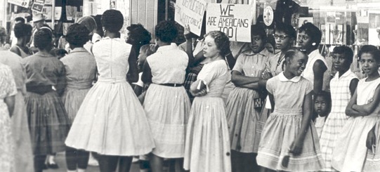 Black women, men and children gathered outside a department store in Oklahoma City protesting during the sit-in movement