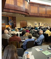 People seated at large round tables in the event center at the Oklahoma History Center listening to speaker Dr. Karlos Hill