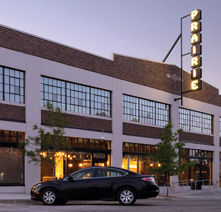 The Prairie Building with a car parked outside at twilight. The neon PRAIRIE sign is lit