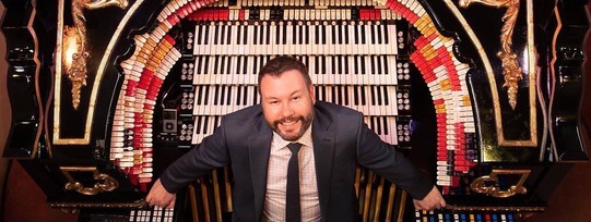 Organist Brett Valliant seated at a Pipe Organ