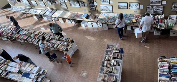 An overhead view of the Research Center Book Sale on the first floor of the History Center. A few people are looking through the stacks