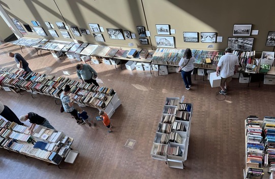 An overhead view of the Research Center Book Sale on the first floor of the History Center. A few people are looking through the stacks