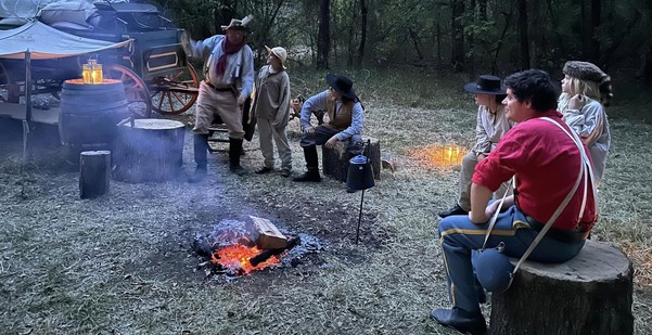 Doaksville scene around a campfire with living history actors listening to a story at twilight.