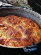 Cinnamon Rolls in a cast iron dutch oven. They are golden brown, cooling off of the fire.