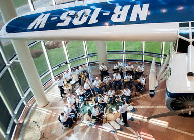 A photo taken of the 145th Army Band performing in the Devon Great Hall of the Oklahoma History Center. The replica of Winnie Mae