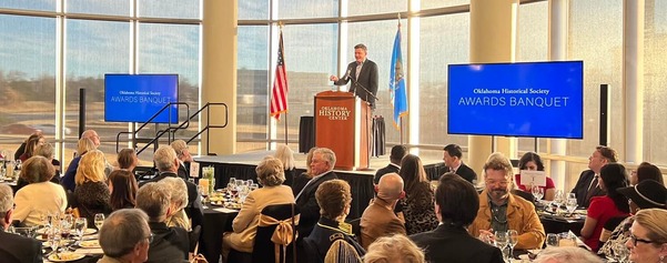 Oklahoma City Mayor David Holt speaks at a podium to guests seated at tables for the OHS Awards Ceremony at the History Center