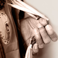 Detail of a photograph showing the closeup of a hand holding beading of a Native American costume "November is NA Heritage Month"