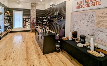 A photo of the Fort Gibson Hospital gift shop. Merchandise hangs from the walls and a counter with register.