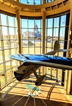 The Oklahoma History Center Devon Great Hall with a photo of the Oklahoma Capitol at a distance and the Winnie Mae airplane at center
