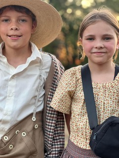 Two children, dressed in 19th century attire stand together in Doaksville