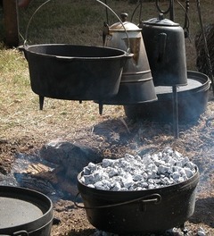 Dutch ovens, a coffee pot cooking over an open fire. Hot coals are on the lid of the dutch oven