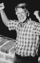 Governor George Nigh at the Great Wall of China, stands with his arms raised in a victorious gesture