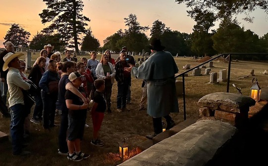 A Volunteer leads a tour at a cemetery at twilight near Fort Towson