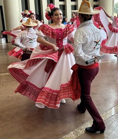 Dancers perform in the Devon Great Hall of the Oklahoma History Center in Oklahoma City. They are wearing brightly colored costumes