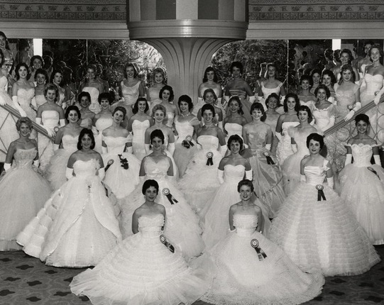Women dressed in white ballgowns gather for a group photo