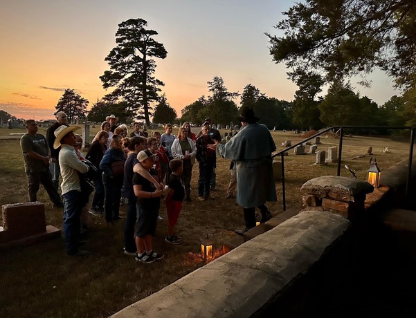 A living history actor gives a candlelight tour to the public at twilight in Doaksville 