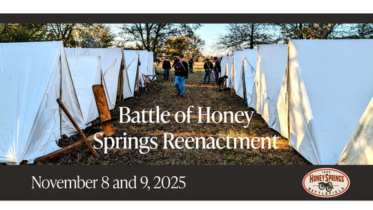 Tents pitched at the Battle of Honey Springs reenactment with soldiers walking between the rows and the dates of the event