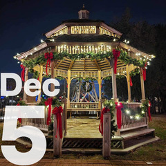 A gazebo decorated for the season with greenery and red bows, and Christmas Lights.