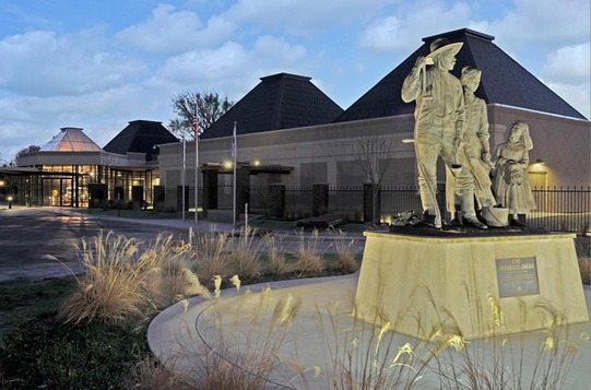 The Cherokee Strip Regional Heritage Center building, stretching behind a 3 figure sculpture of man, woman and child homesteaders.