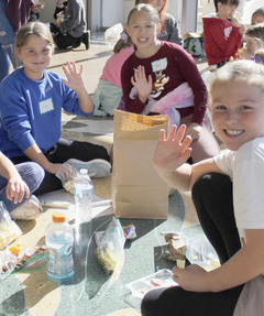 Smiling schoolchildren seated on the floor of the Oklahoma History Center hall stopping for lunch during a field trip.