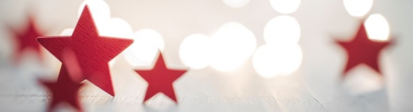 Wooden stars decorate a table and lights are seen glistening around them.