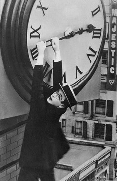 Harold Lloyd hangs from the hour hand of a large oversized clock.