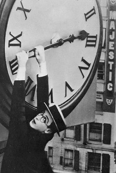 Harold Lloyd hangs from the hour hand of a large oversized clock.