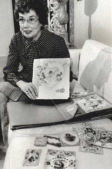 A woman holds up one in a collection of vintage valentines she is sorting through