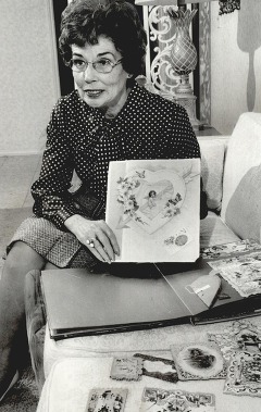 A woman holds up one in a collection of vintage valentines she is sorting through